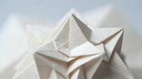 White paper origami geometric shapes folded into angular forms creating abstract sculptural composition on neutral background for creative projects.
