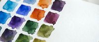 Watercolor paint palette with vibrant color swatches on white paper. Art supplies for creative painting, drawing and artistic projects.