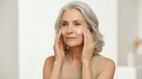 Mature Caucasian woman applying anti-aging cream to face, skincare routine for seniors, beauty wellness concept for cosmetic advertising campaigns.