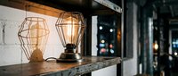 Vintage industrial table lamps with geometric wire cages on wooden shelf, warm ambient lighting for home decor and interior design projects.