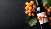 Fresh wine bottle with peach-colored bow decoration alongside ripe golden grapes and green vine leaves against dark moody background, elegant composition for wine marketing.