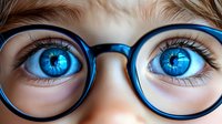 Close up view of bright blue eyes with long eyelashes seen through round blue eyeglasses frames, showing enhanced vision and optical care concept.