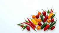 Assorted fresh chili peppers and bell peppers arranged on white background, isolated for culinary, cooking, and food design projects.