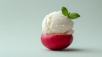 Fresh vanilla ice cream scoop in red bowl with mint garnish on clean background for dessert menu and food photography concepts.