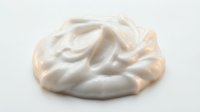 Creamy beige whipped cosmetic product with soft swirled texture isolated on white background, suitable for skincare packaging and beauty marketing materials.