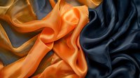 Luxurious silk fabric in orange and navy blue colors with elegant folds and waves creating dramatic contrast and flowing texture for fashion design background.