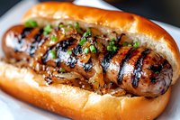 Grilled sausage with caramelized onions and fresh herbs on toasted brioche bun, close-up view showing juicy meat and char marks for food service and menu.