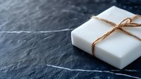 White gift box tied with natural jute twine on dark slate surface. Minimalist present wrapping for holidays, birthdays, and special occasions.