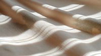 Abstract flowing fabric waves in soft beige and white tones creating elegant textile background with natural light shadows for modern interior design projects.
