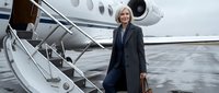 Mature woman in business attire descending airplane stairs at tarmac, corporate travel and executive lifestyle concept for professional settings.