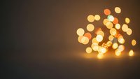 Warm golden bokeh lights creating magical atmosphere on dark brown background for holiday celebrations and festive decorations.