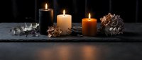 Autumn candles burning on dark slate with pine cones and dried leaves creating cozy seasonal atmosphere for home decor and relaxation.