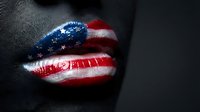 Glossy lips painted with American flag stars and stripes pattern on dark skin background for patriotic makeup and beauty concepts.