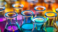 Laboratory glassware with colorful liquid chemicals in glass beakers and flasks against vibrant background with bokeh effect creates scientific atmosphere.