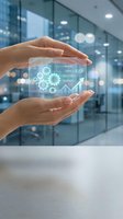 Hands protecting holographic business analytics dashboard with gears and growth charts in modern office environment for digital transformation concepts.