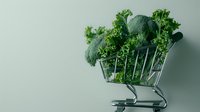 Fresh green broccoli and curly kale leaves in shopping cart on mint background, minimalist food composition for healthy eating and grocery concept.
