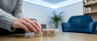 Person arranging wooden blocks with star ratings on desk in modern living room for customer feedback and quality assessment concepts.