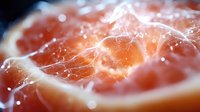 Fresh juicy grapefruit macro shot with water drops and natural light. Vibrant pink flesh and citrus pulp closeup showing texture and moisture.