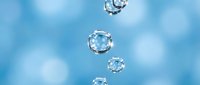 Transparent water droplets floating on a soft blue bokeh background, conveying freshness, purity, and hydration for wellness or cosmetic design.
