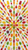 Colorful gummy candy assortment arranged in radial pattern on white background. Sweet treats including bears, worms, rings in vibrant rainbow colors for confectionery.