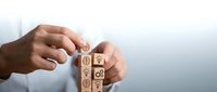 Businessman arranging wooden blocks with brain, gear, and lightbulb icons, symbolizing innovation, strategy, and creative thinking in business.