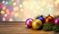 Colorful Christmas ornaments with pine branches on wooden table against festive bokeh background.