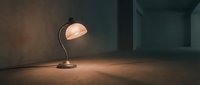 Vintage desk lamp with warm glow illuminating empty concrete room interior, creating atmospheric lighting for home decor, office design, and architectural visualization projects.
