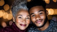 African American senior mother and adult son sharing tender moment, smiling at camera with warm bokeh lights in background, expressing family love and connection.