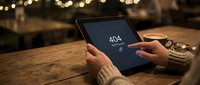 Person holding tablet displaying 404 error message at wooden desk with warm bokeh lights, suitable for web design, error pages, and digital technology concepts.