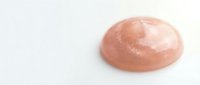 Pink rose gold metallic lip gloss drop on white background. Cosmetic product texture for beauty and makeup industry applications.