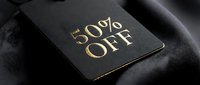 Luxury black price tag with gold foil 50% off text on dark fabric, elegant discount label for fashion retail and sale promotions.