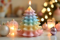 Pastel rainbow Christmas tree candle with flame surrounded by ornaments and warm bokeh lights creating festive holiday atmosphere for seasonal decor.