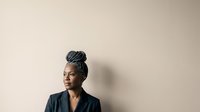 Mature woman with gray hair in professional black blazer against neutral beige background, suitable for corporate, business, and leadership concepts.