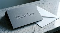 Gray embossed thank you card with white envelope on marble surface, elegant stationery for gratitude, appreciation, and celebration greetings.