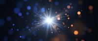 Bright starburst light explosion with radiant beams and glowing bokeh particles on dark background for cosmic energy and celebration designs.