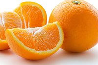 Fresh juicy orange fruit sliced and whole on white background, showing bright pulp segments and textured peel, isolated for food and beverage marketing.