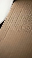 Embossed ornamental pattern on brown kraft paper with elegant floral motifs creating textured surface for luxury packaging and stationery design projects.