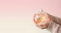 Hands holding glowing light bulb with warm illumination against soft pink background representing innovation creativity and bright ideas for business concepts.