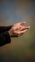 Male hand extended in open gesture showing palm and fingers against soft blurred background suggesting help, support, giving or receiving concept.