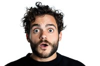 Young Mediterranean man with curly dark hair and beard showing surprised shocked facial expression with wide open eyes and mouth against white background.