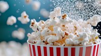 Fresh popcorn explosion from classic striped container against teal background, with kernels and salt particles suspended in dynamic motion.