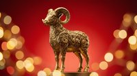 Golden ram figurine with curved horns standing against red background with warm bokeh lights, suitable for holiday decorations, luxury gifts, and festive design projects.