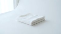 Soft white folded terry towel on a clean white surface, conveying freshness, hygiene, and minimalist spa or hotel bathroom style.
