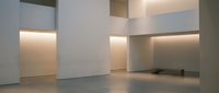Modern minimalist interior with clean white walls and warm ambient lighting creating geometric shadows and architectural depth for contemporary design projects.