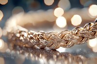 Luxurious golden rope chain necklace with twisted pattern macro shot on reflective surface against soft bokeh background, showcasing intricate jewelry details.