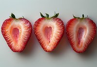 Fresh ripe strawberry halves arranged in row showing juicy red flesh and detailed internal texture on light gray background, macro food photography.