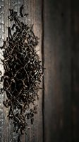Dried tea leaves scattered on weathered wooden surface with dramatic lighting, suitable for beverage, culinary, and food photography projects.