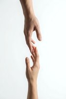 Two hands reaching toward each other in helping gesture on white background symbolizing support, connection, teamwork and human assistance concept.