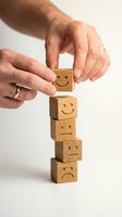 Hands stacking wooden blocks with emotion faces showing customer satisfaction rating and feedback concept for business service quality evaluation.