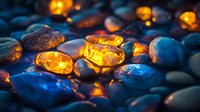 Glowing amber stones among dark blue pebbles create magical atmosphere with warm light effects, mystical illumination on smooth river rocks for spa and wellness.
